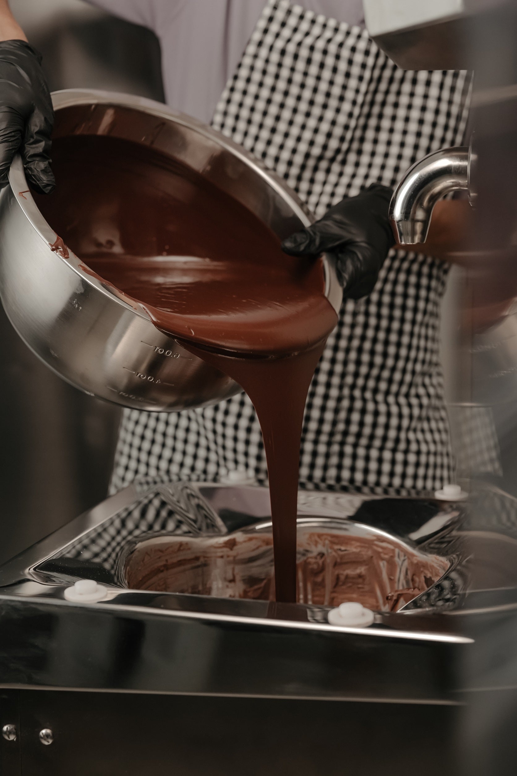 Chocolatier hand-pouring tempered chocolate in the workshop